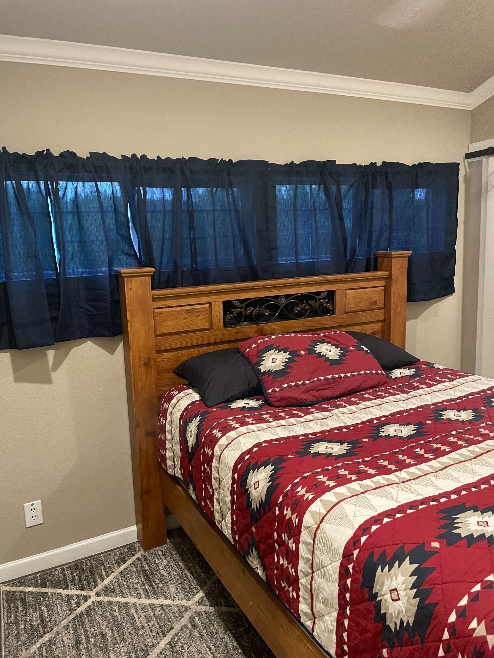 A bedroom with a bed and a window with blue curtains.