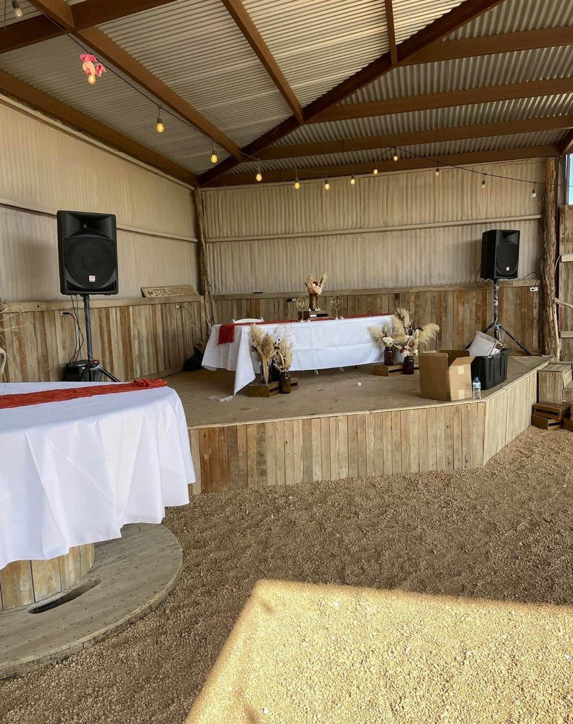 There is a stage in the middle of the room with tables and speakers.