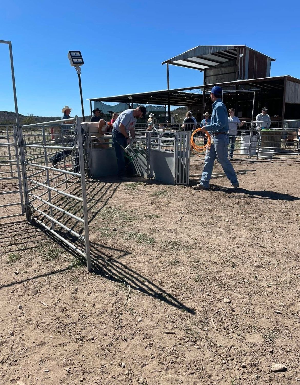 A group of people are working on a fence in a dirt field.