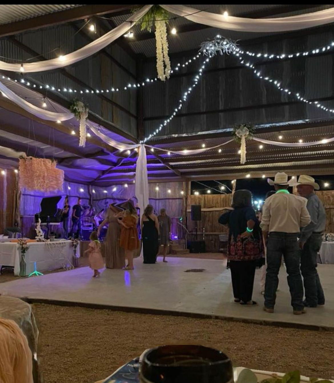 A group of people are standing on a dance floor at a wedding reception.
