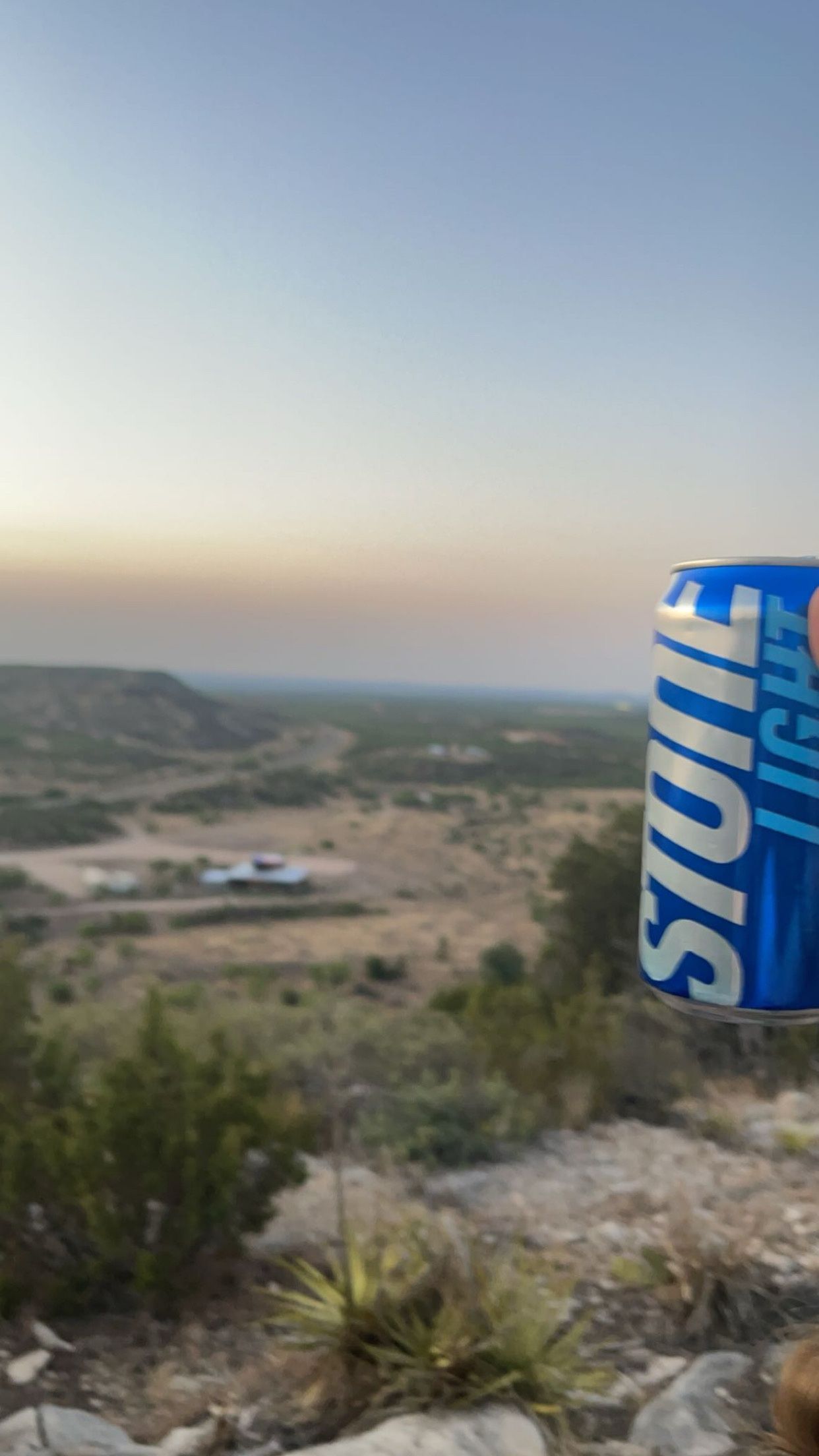 A can of stout light beer is sitting on top of a hill.