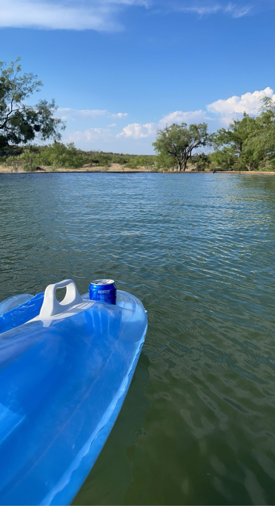 A blue boat is floating on top of a lake.