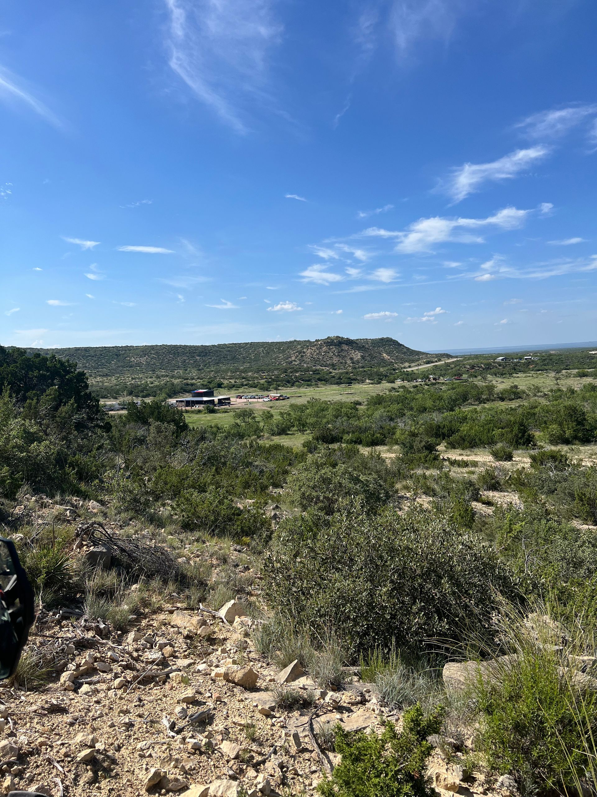 A view of a lush green field from a hill on a sunny day.