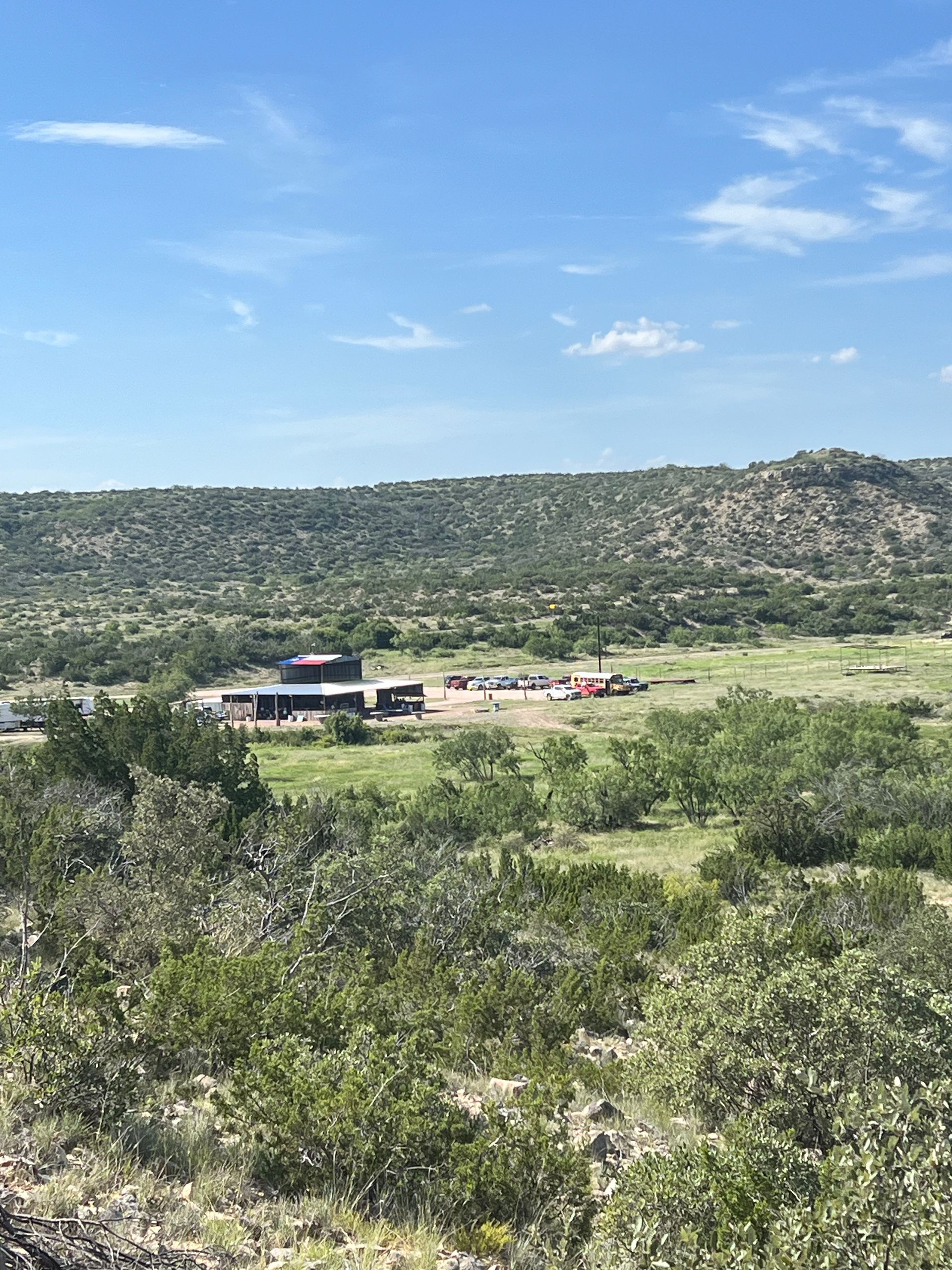 There is a house in the middle of a field surrounded by trees.