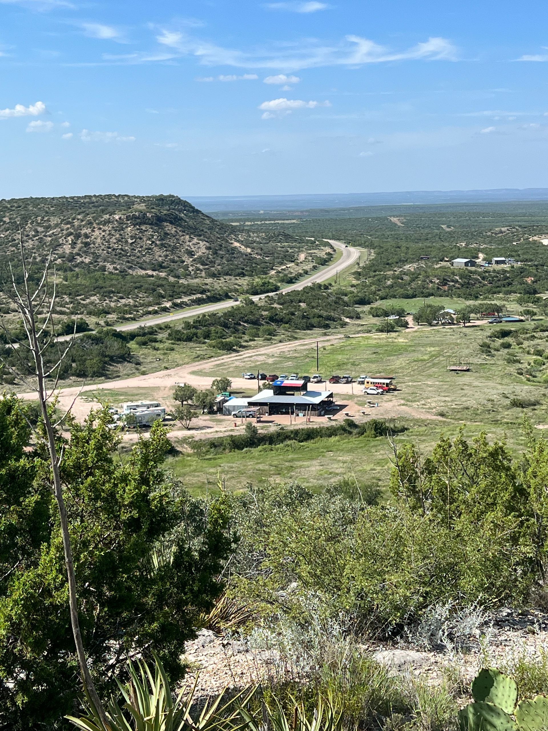 A view of a valley from a hill with a house in the middle of it.