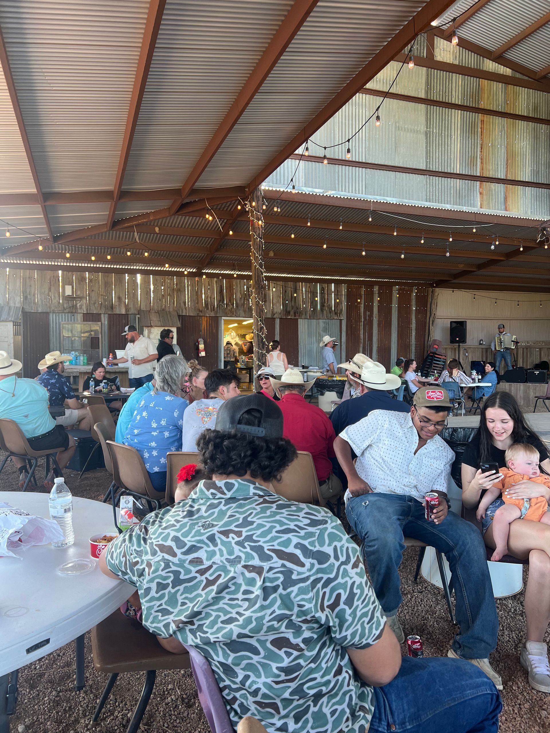 A group of people are sitting at tables in a barn.
