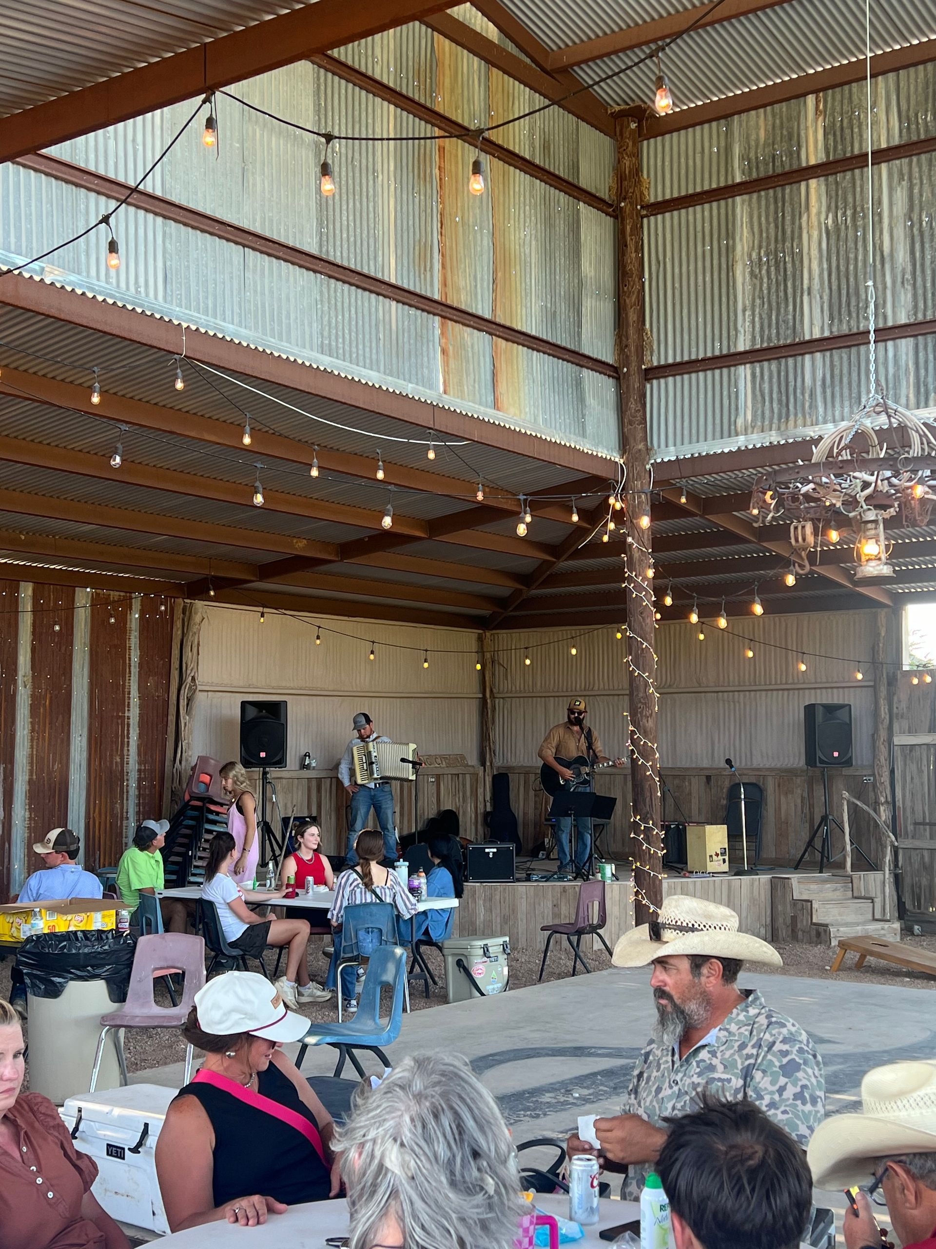 A group of people are sitting at tables in a barn.