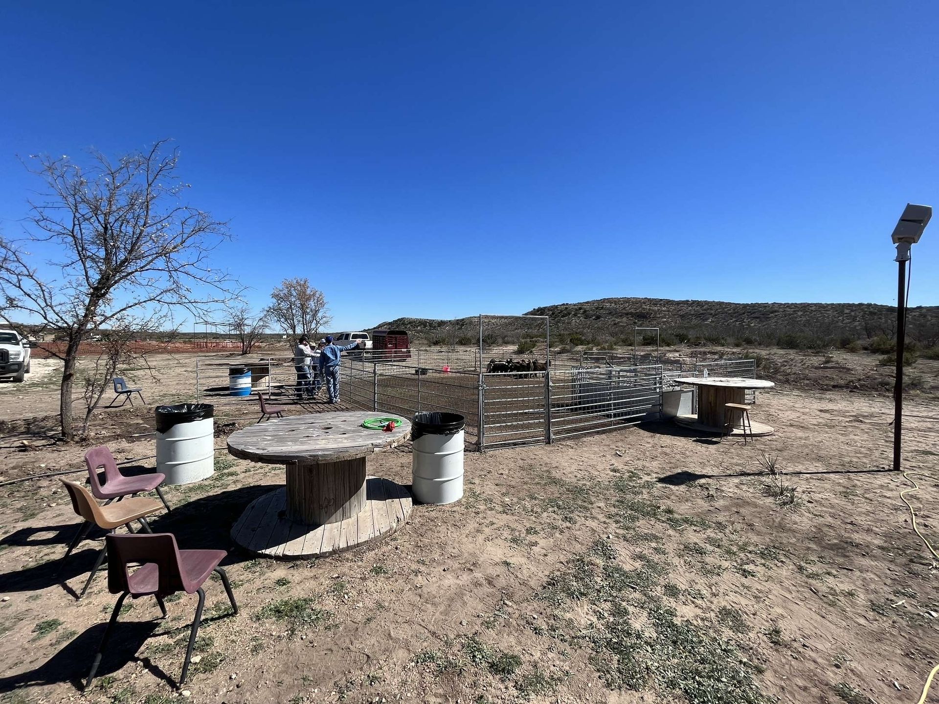 A table and chairs are sitting in the middle of a dirt field.