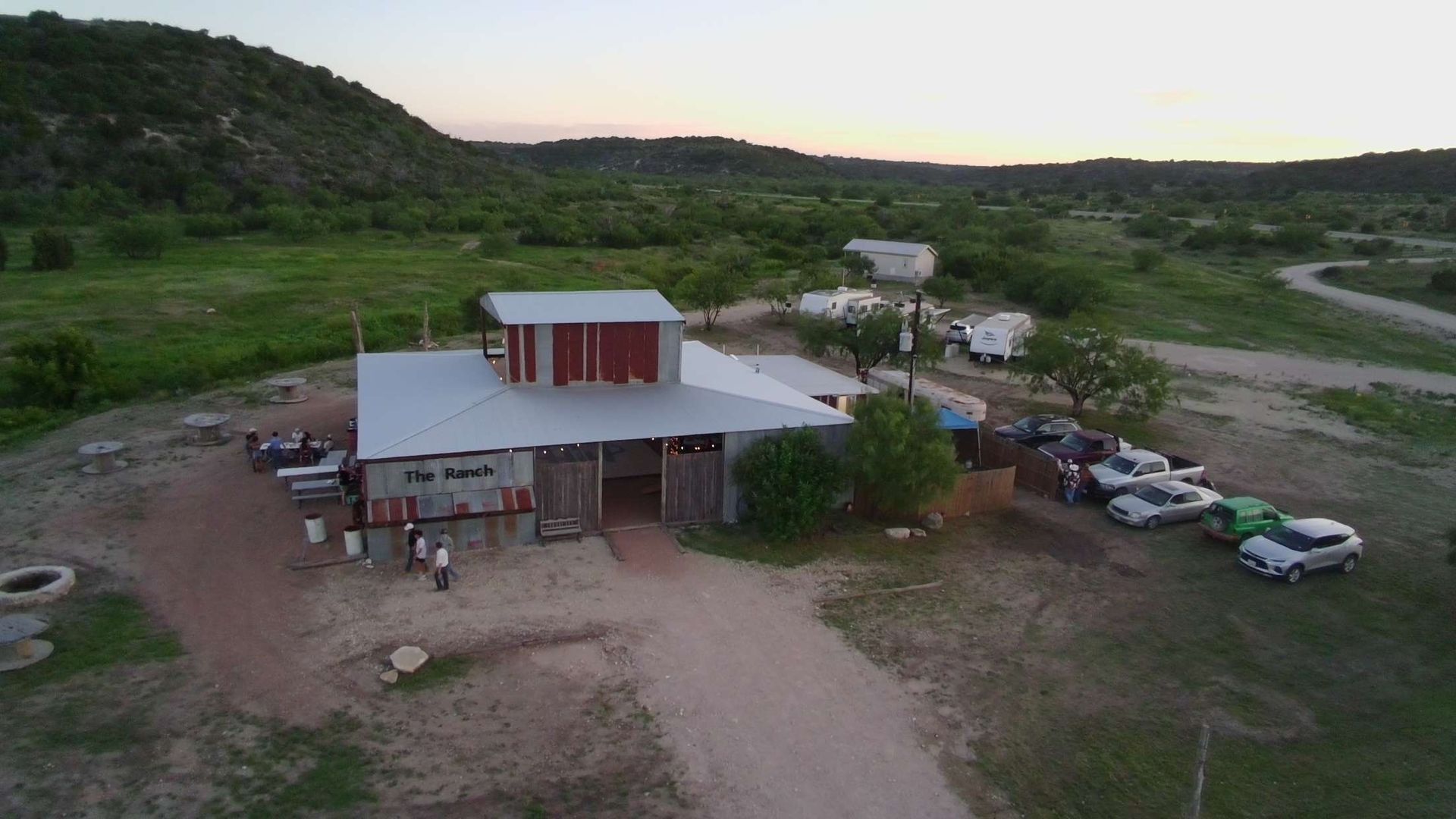 An aerial view of a building in the middle of a field with cars parked in front of it.