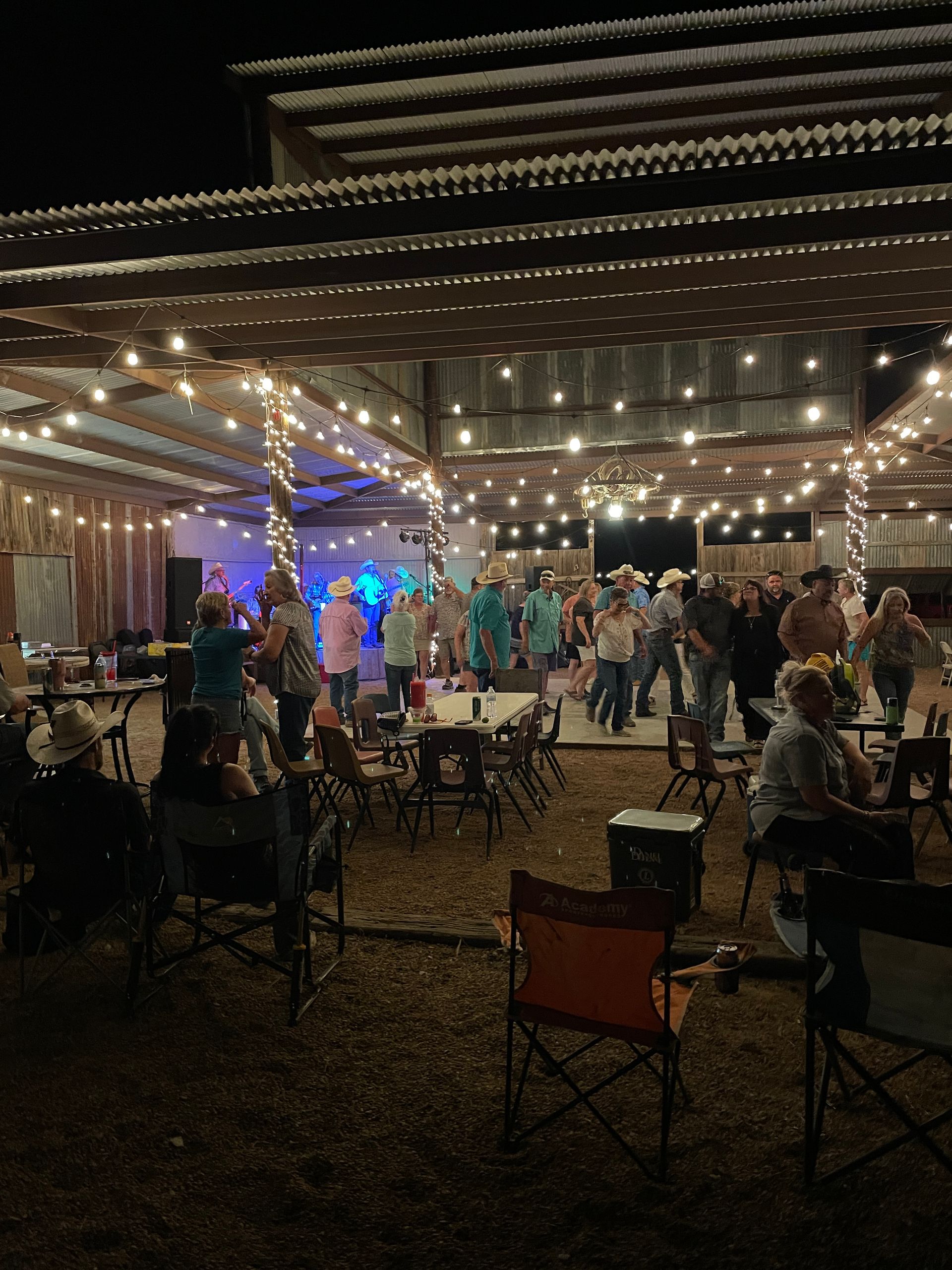 A large group of people are dancing under a canopy at a party.