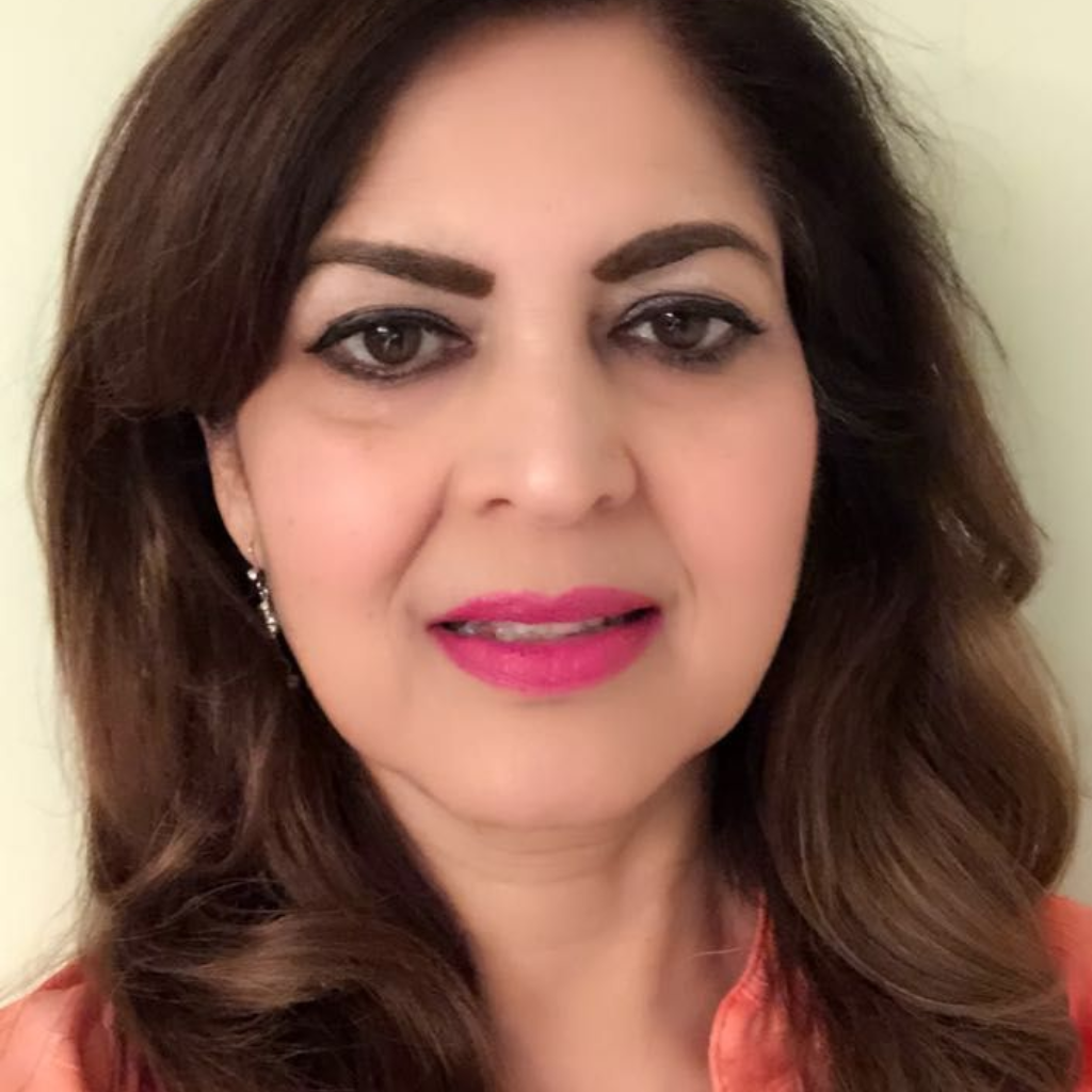Woman with brown hair, wearing a pink shirt, smiles, and has pink lipstick.
