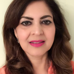 Woman with brown hair, wearing a pink shirt, smiles, and has pink lipstick.
