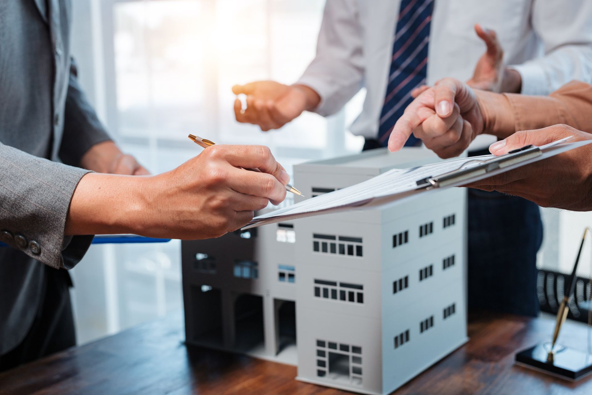 People signing documents over a model building.