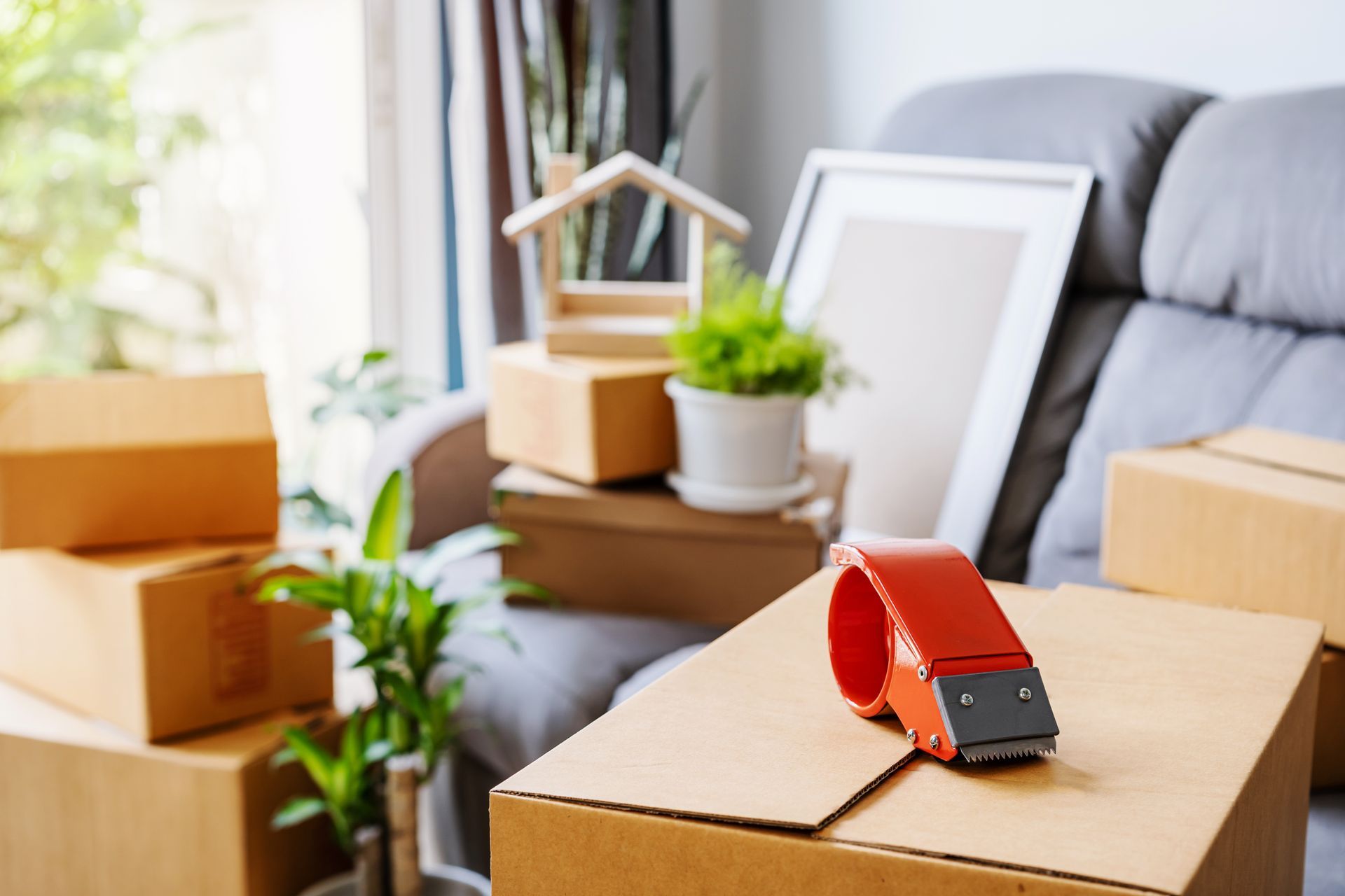 Moving boxes stacked near a sofa with a tape dispenser on top.