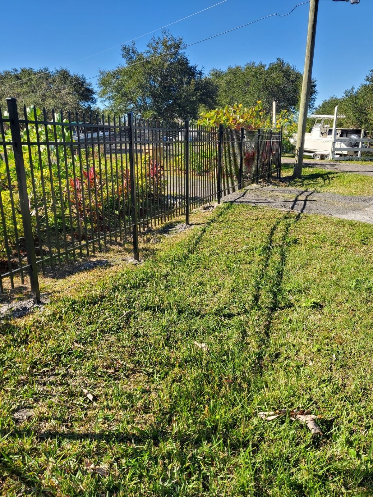 A black metal fence surrounds a lush green field.