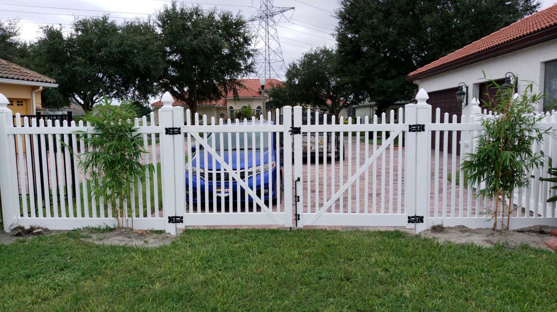A white picket fence with a gate in front of a house.