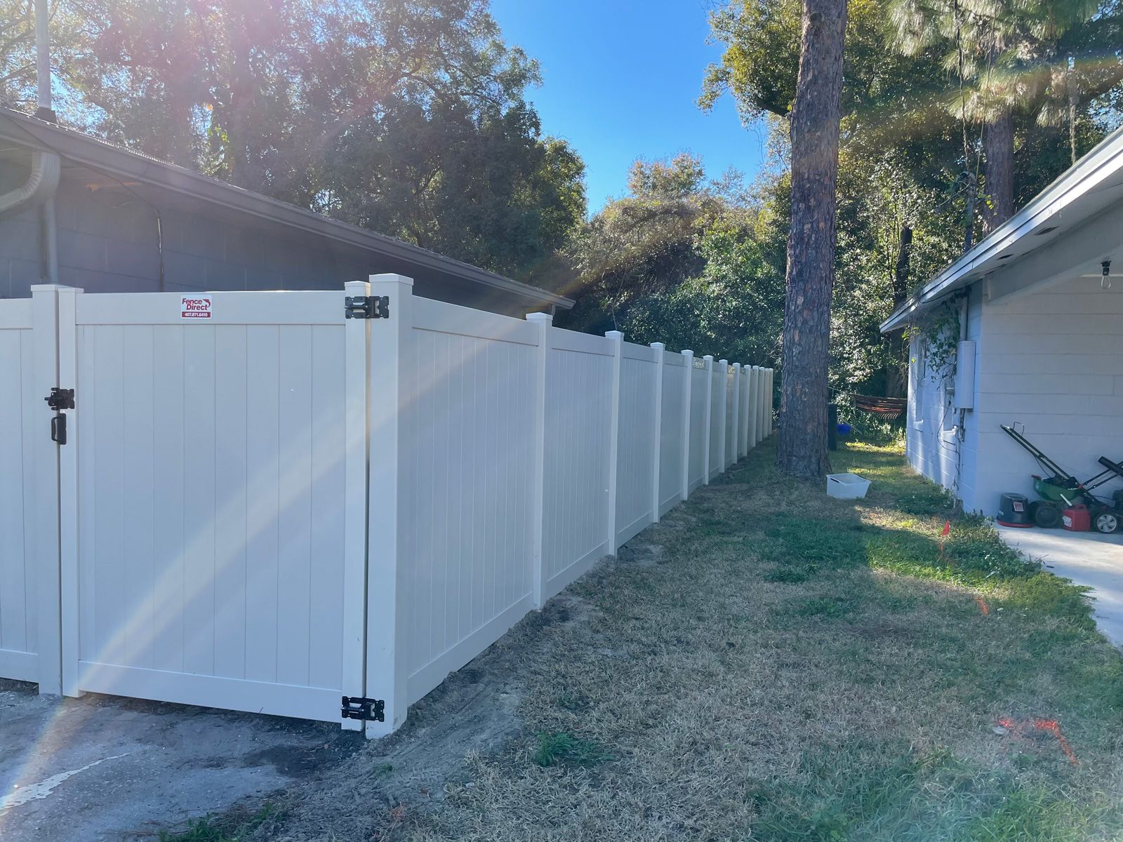 A white vinyl fence with a gate in front of a house.