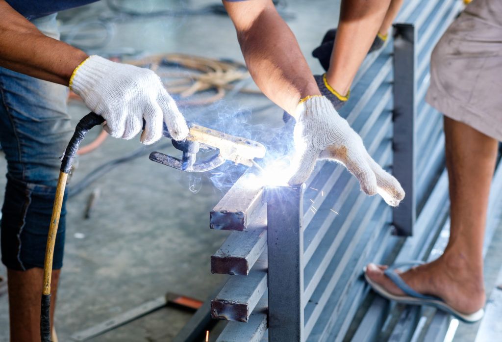 A man is welding a piece of metal in a factory.