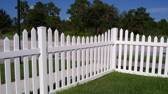 A white picket fence surrounds a lush green yard.