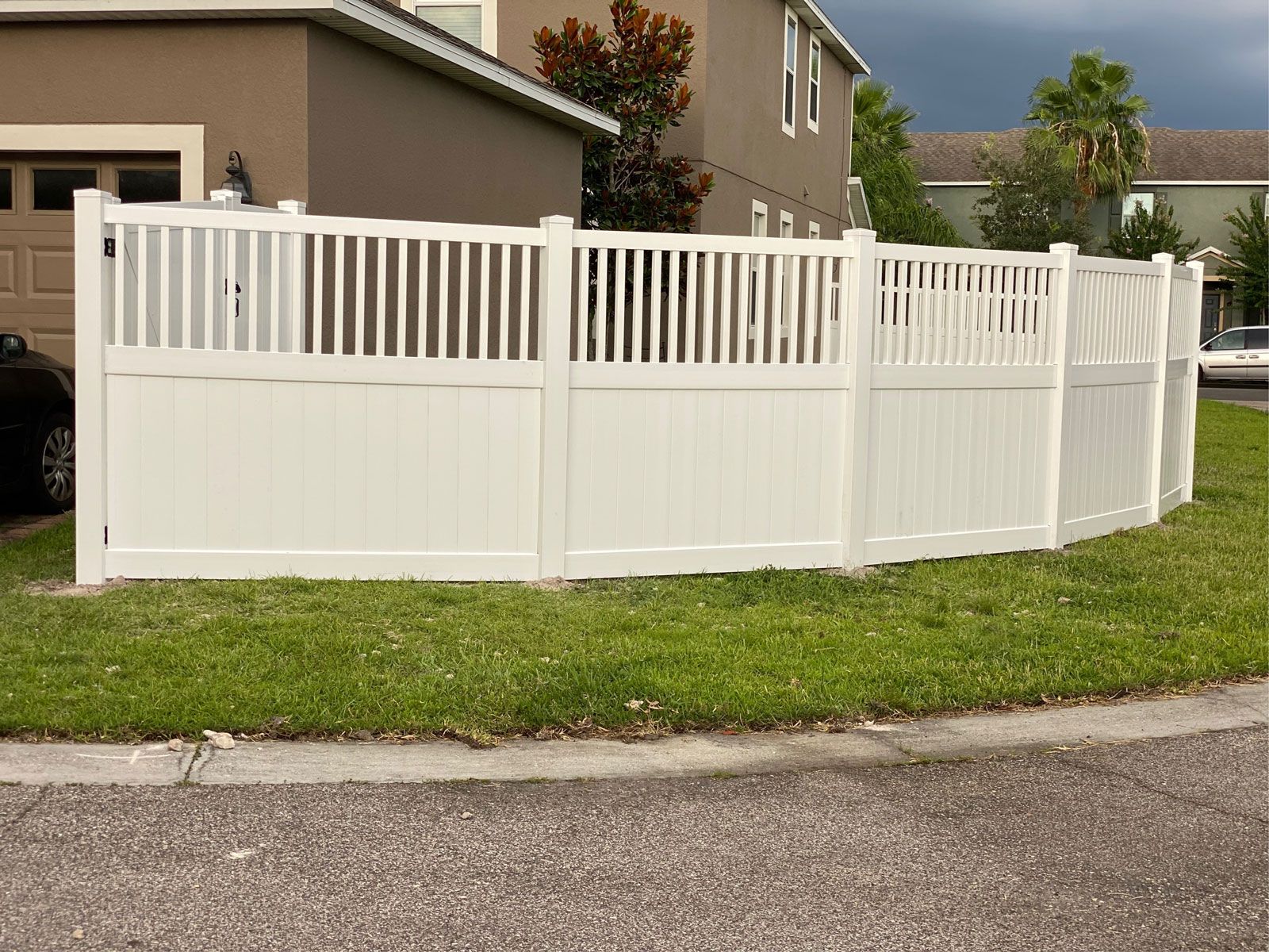 A white fence is sitting in the grass in front of a house.