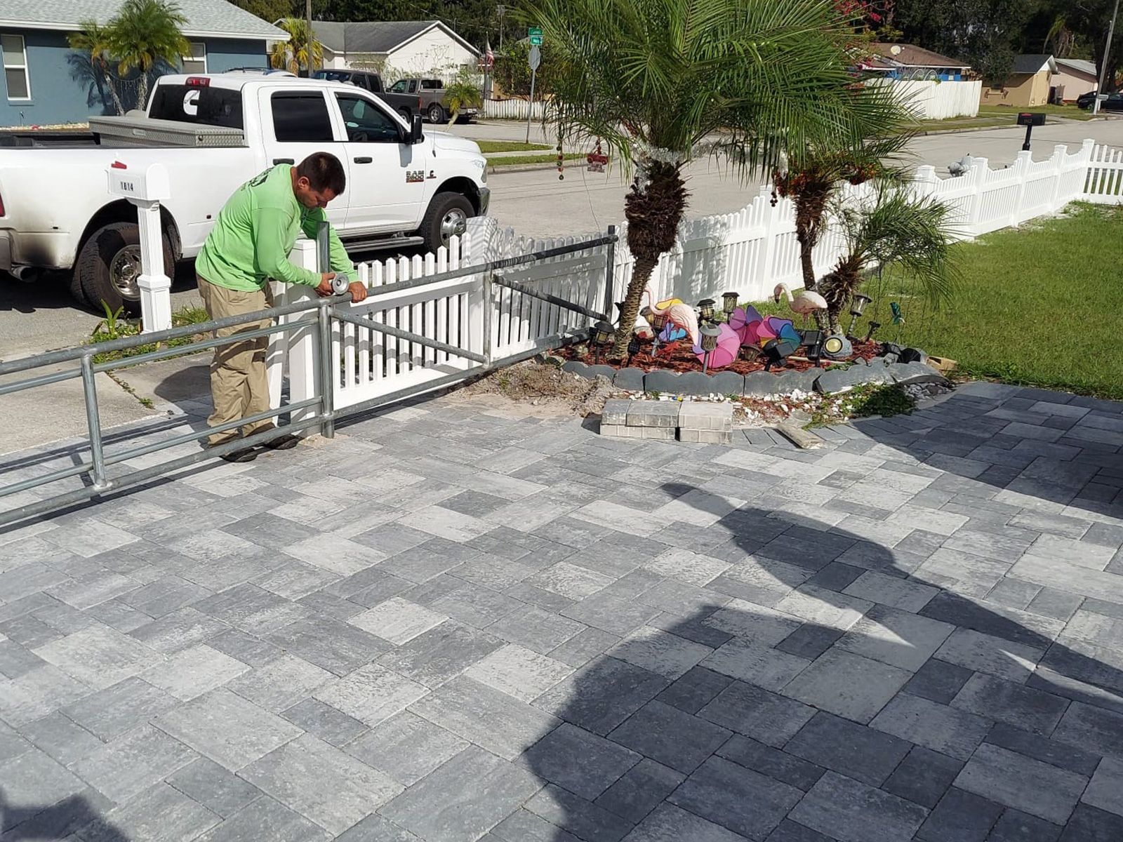 A man is working on a fence in front of a white truck.