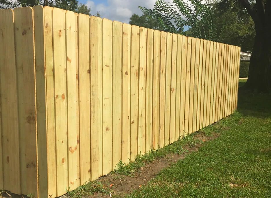 A wooden fence is sitting in the grass next to a tree.