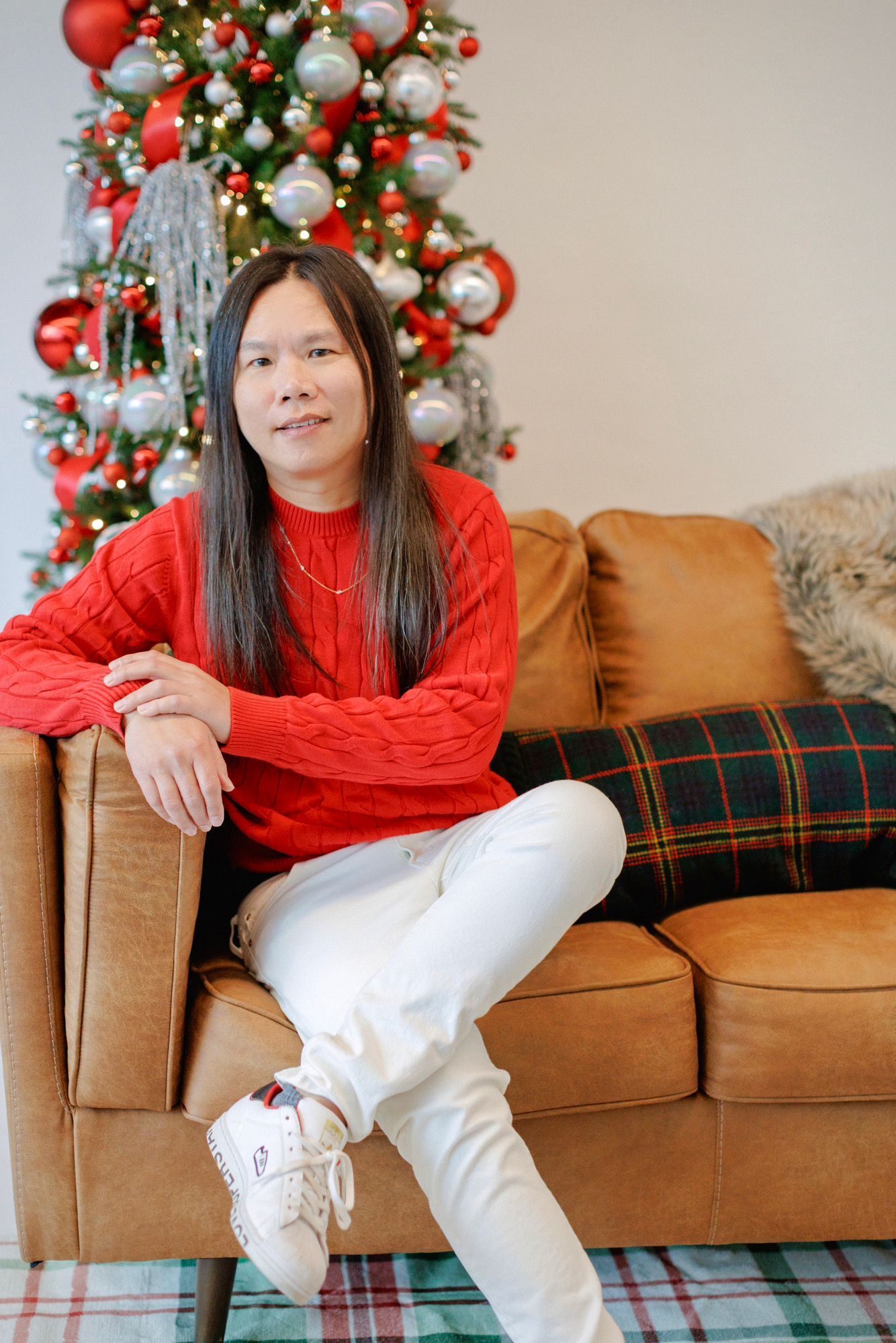 A woman is sitting at a desk with a laptop and a vase of flowers.