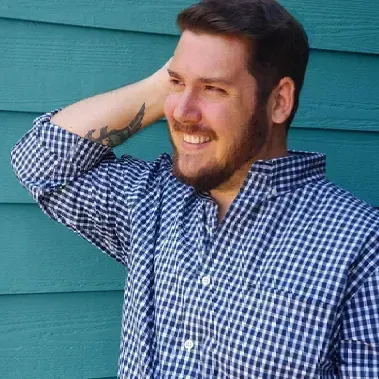A man with a beard is wearing a blue and white checkered shirt.