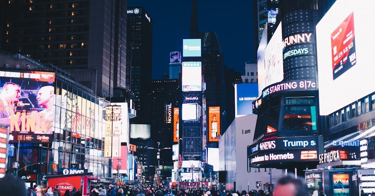 A crowd of people are walking down a busy city street at night.