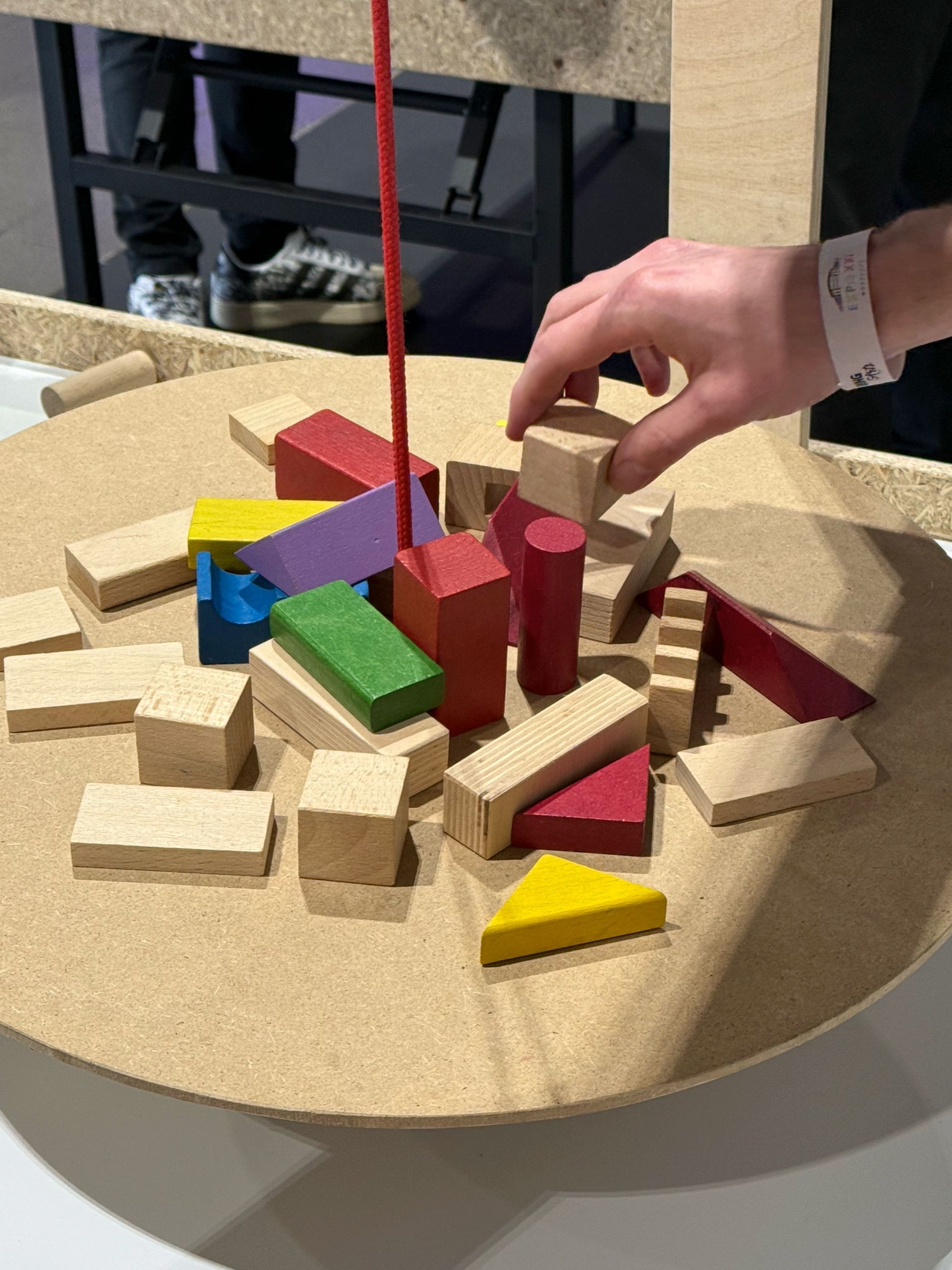 Osoba bawi się drewnianymi klockami na stole.