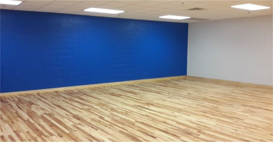 An empty room with a blue wall and a wooden floor