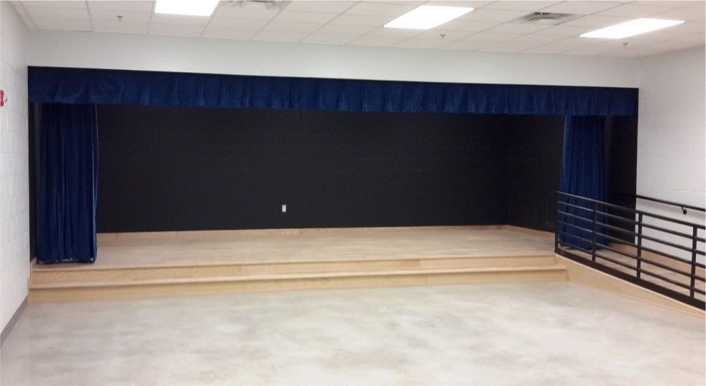 An empty stage with blue curtains and wooden steps