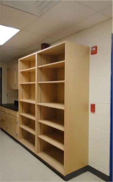 A row of shelves in a room with a fire alarm on the wall