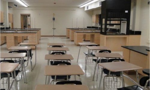 An empty classroom with rows of desks and chairs