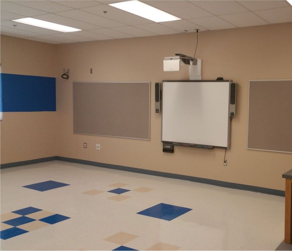 An empty classroom with a white board and projector