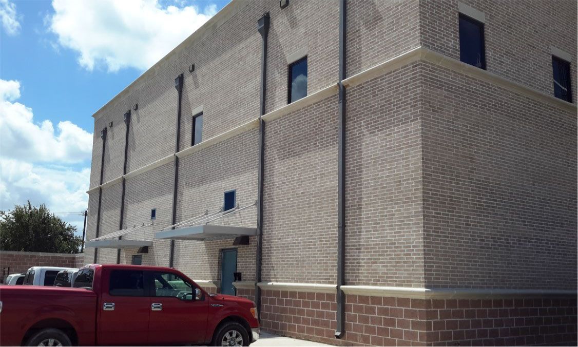 A red truck is parked in front of a large brick building.
