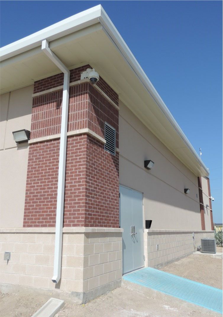 A brick building with a white gutter on the side