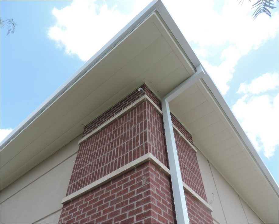 A brick building with a white gutter on the side