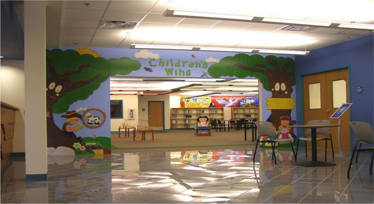 A children 's area in a library with a mural on the wall