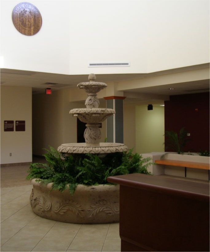 A fountain in the middle of a room with a red exit sign above it