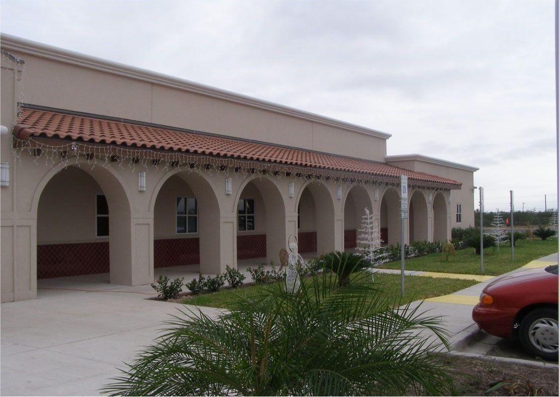 A red car is parked in front of a building with arches