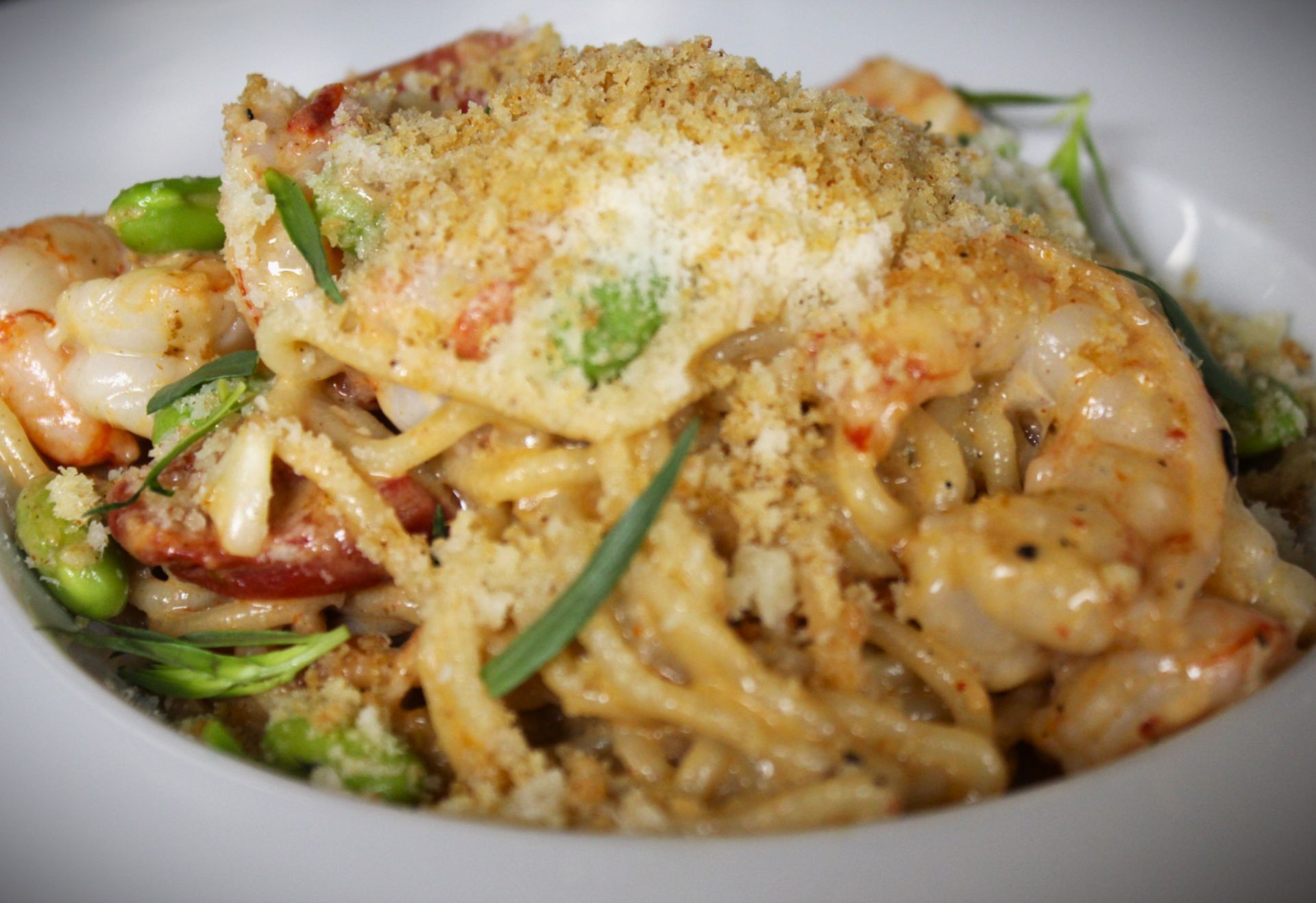 A close up of a plate of food with noodles and shrimp on a table.