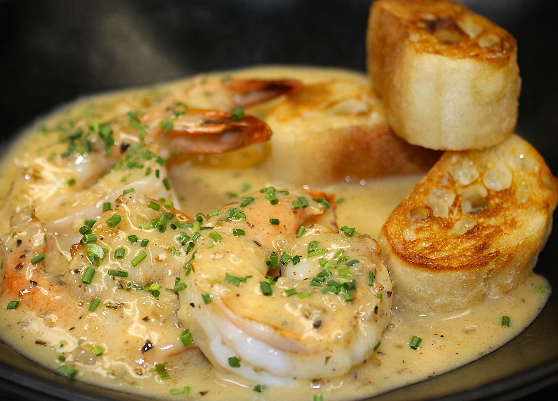 A close up of a plate of food with shrimp and bread on a table.