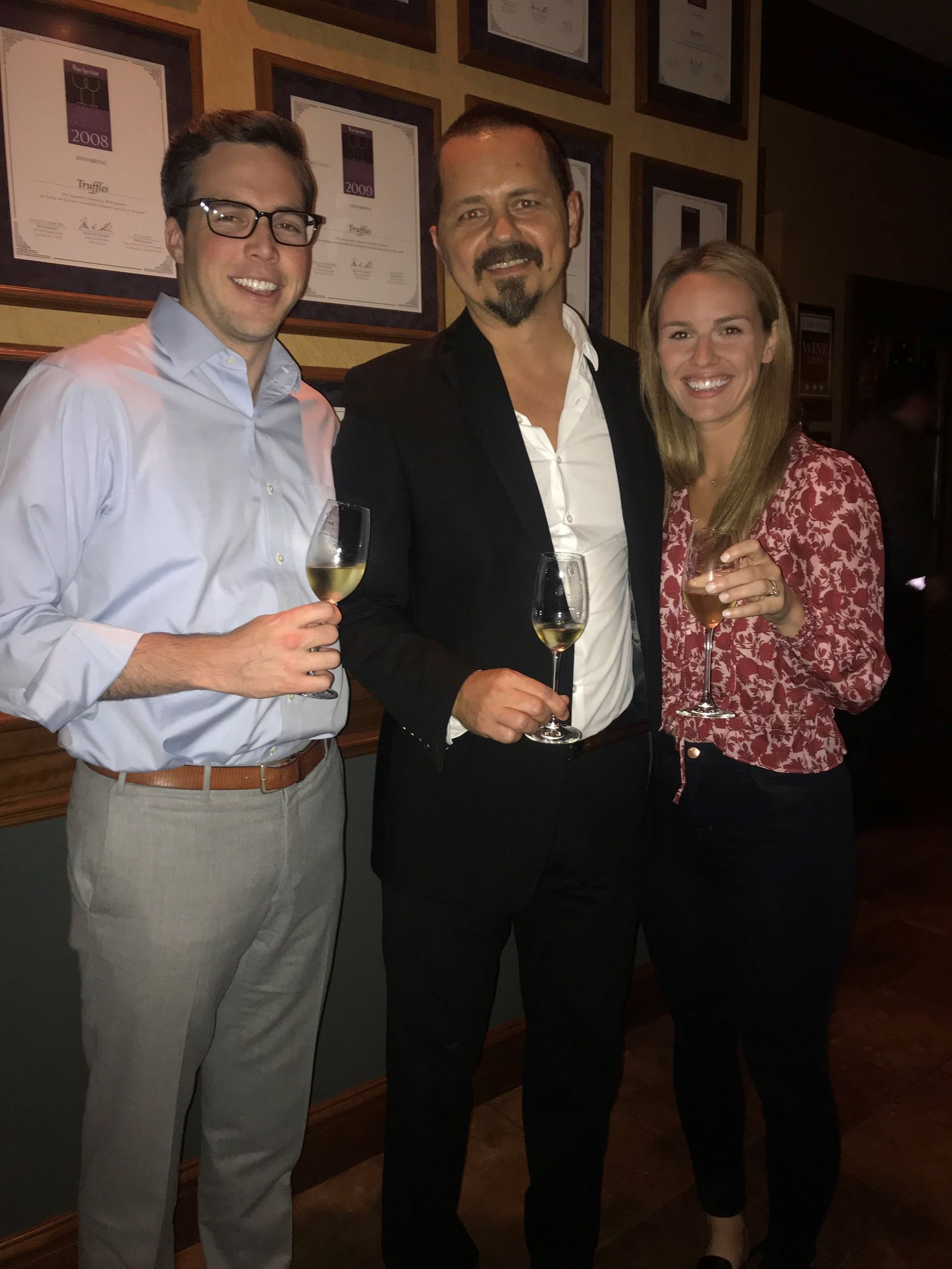 Three people standing next to each other holding wine glasses