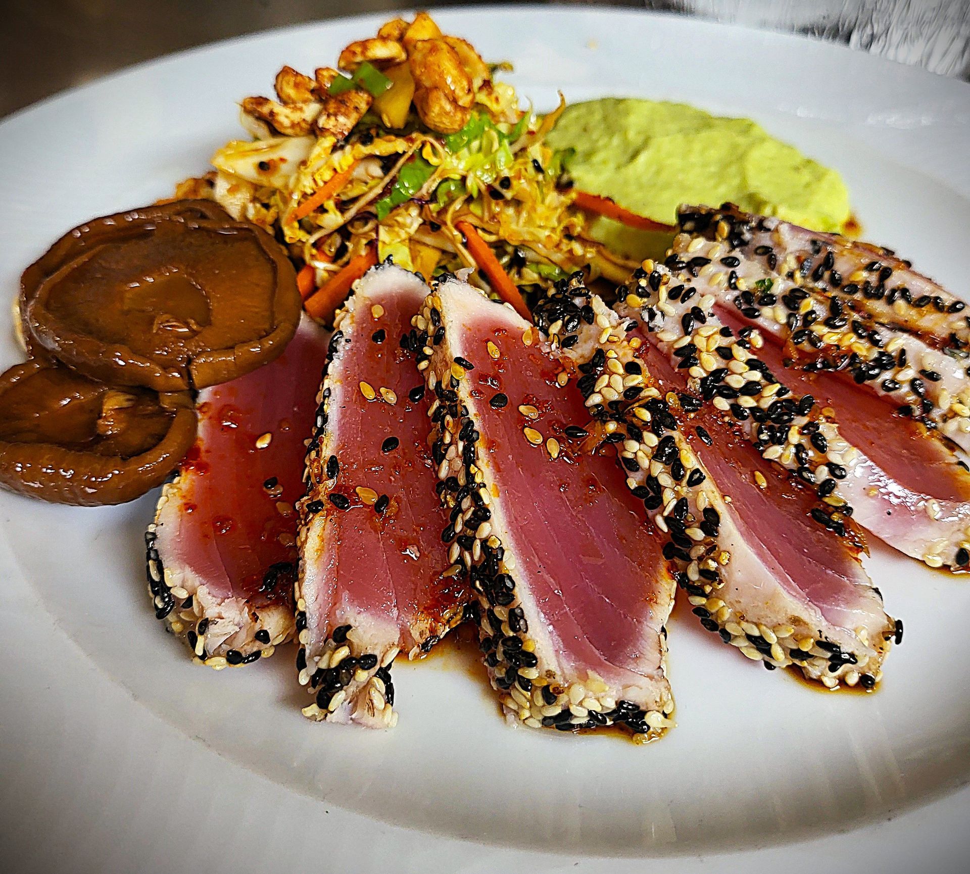 A white plate topped with sliced meat and vegetables