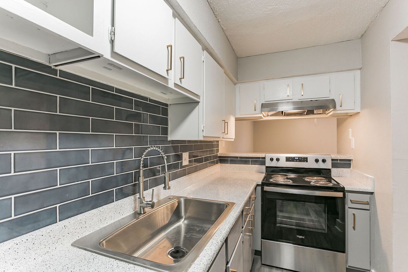Kitchen with white cabinets, dark gray tile backsplash, and stainless steel appliances.