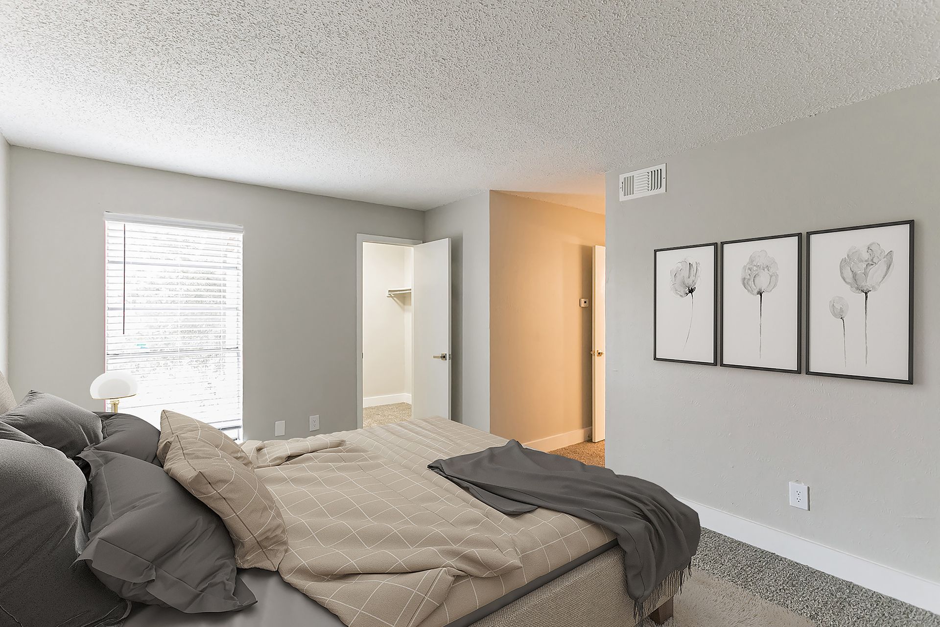 Bedroom with bed, pillows, artwork, closet, and window. Walls are grey with a textured ceiling.