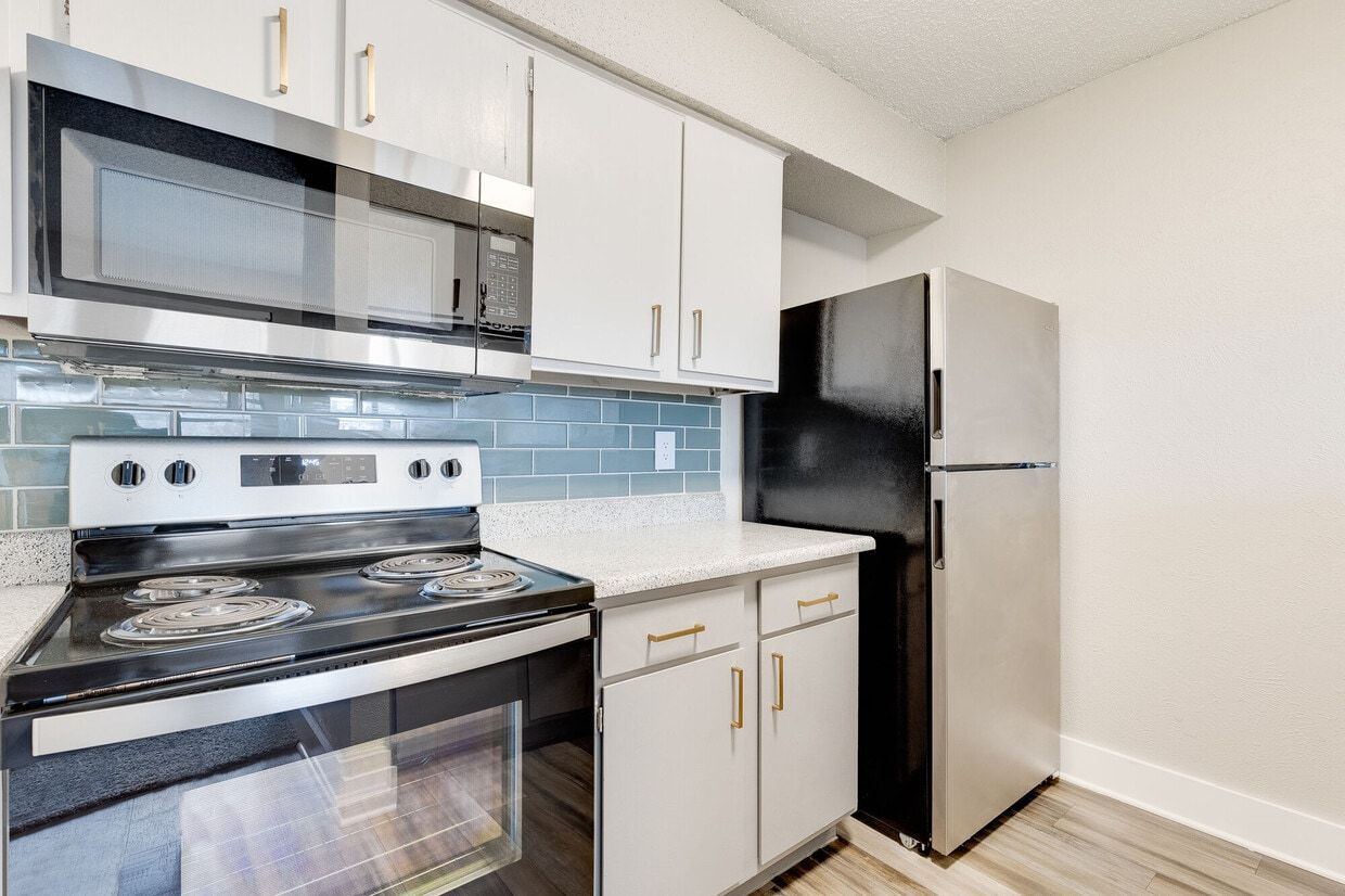 Modern kitchen with white cabinets, stainless steel appliances, and blue tile backsplash.