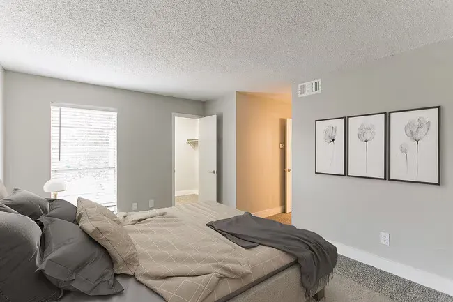 Bedroom with bed, gray walls, artwork, and closet; neutral colors.