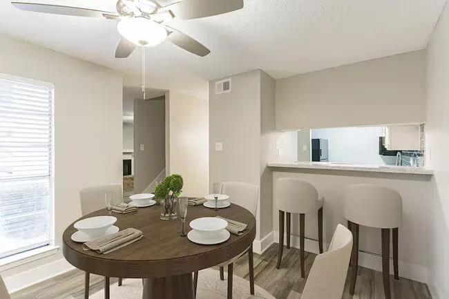 Dining room with a round table, bar stools, and open kitchen.